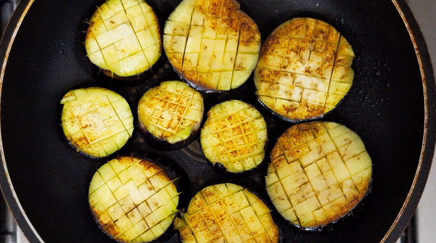 Lightly oil the pan and grill the thick-cut eggplant slices with shallow crisscross cuts on the surface.