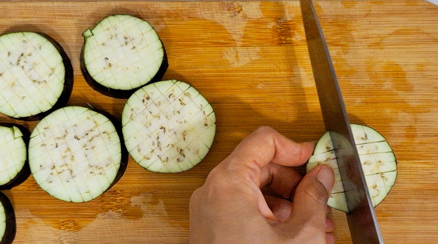 Start by making shallow crisscross cuts on the thickly sliced eggplant to help it absorb the sauce better